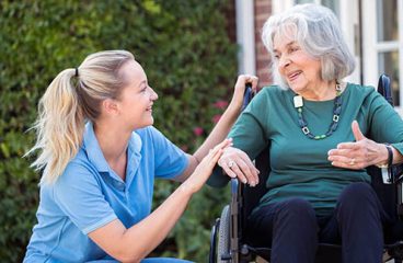 Carer Pushing Senior Woman In Wheelchair Outside Home Carer Pushing Senior Woman In Wheelchair Outside Home